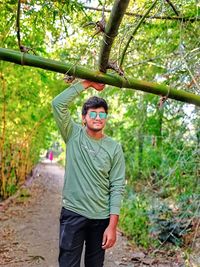 Portrait of young man standing against trees