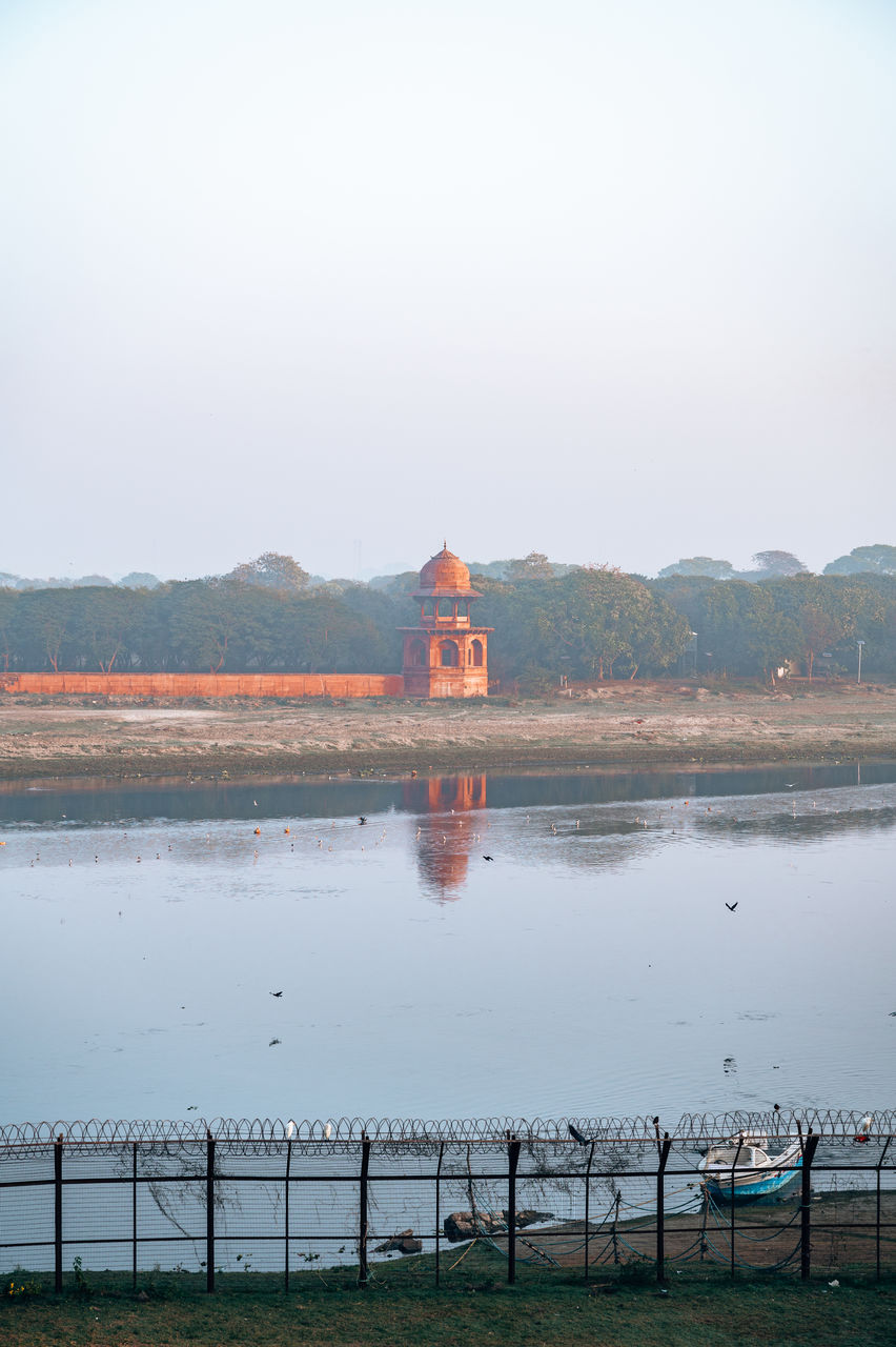 water, reflection, sky, architecture, sea, nature, morning, built structure, environment, travel destinations, shore, landscape, travel, reservoir, building, beauty in nature, scenics - nature, tourism, land, horizon, tranquility, building exterior, outdoors, no people, religion, clear sky, body of water, day, coast, mountain, tranquil scene, transportation, beach, dusk, history, city