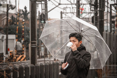 Man holding umbrella standing in rain