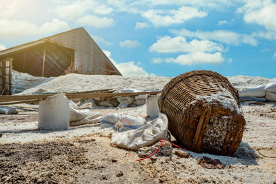 Barn with brine salt in sack. pile of organic sea salt and bamboo basket in front of barn with blue 