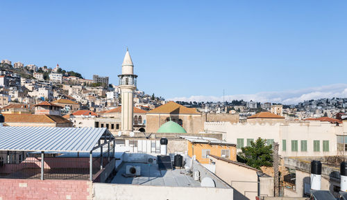 View of buildings in city against clear blue sky