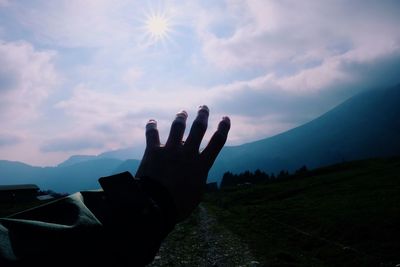 Man hand on mountain against sky