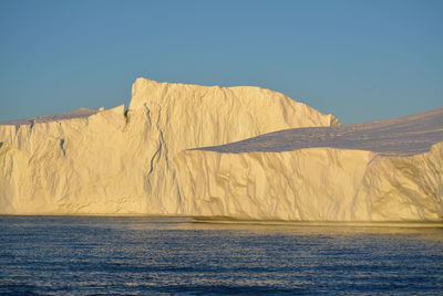 Scenic view of sea against clear sky with beautiful icebergs in the midnight sun ilulissat greenland