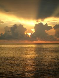 Scenic view of sea against dramatic sky during sunset