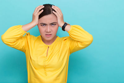 Portrait of young woman against blue background