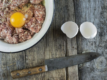 Directly above shot of minced meat with egg yolk in bowl by knife on table