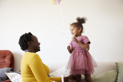 Mother and daughter playing together at sofa