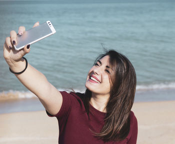 Woman taking selfie while standing at beach