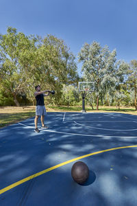 Young man exercising with kettlebell on basketball court at park