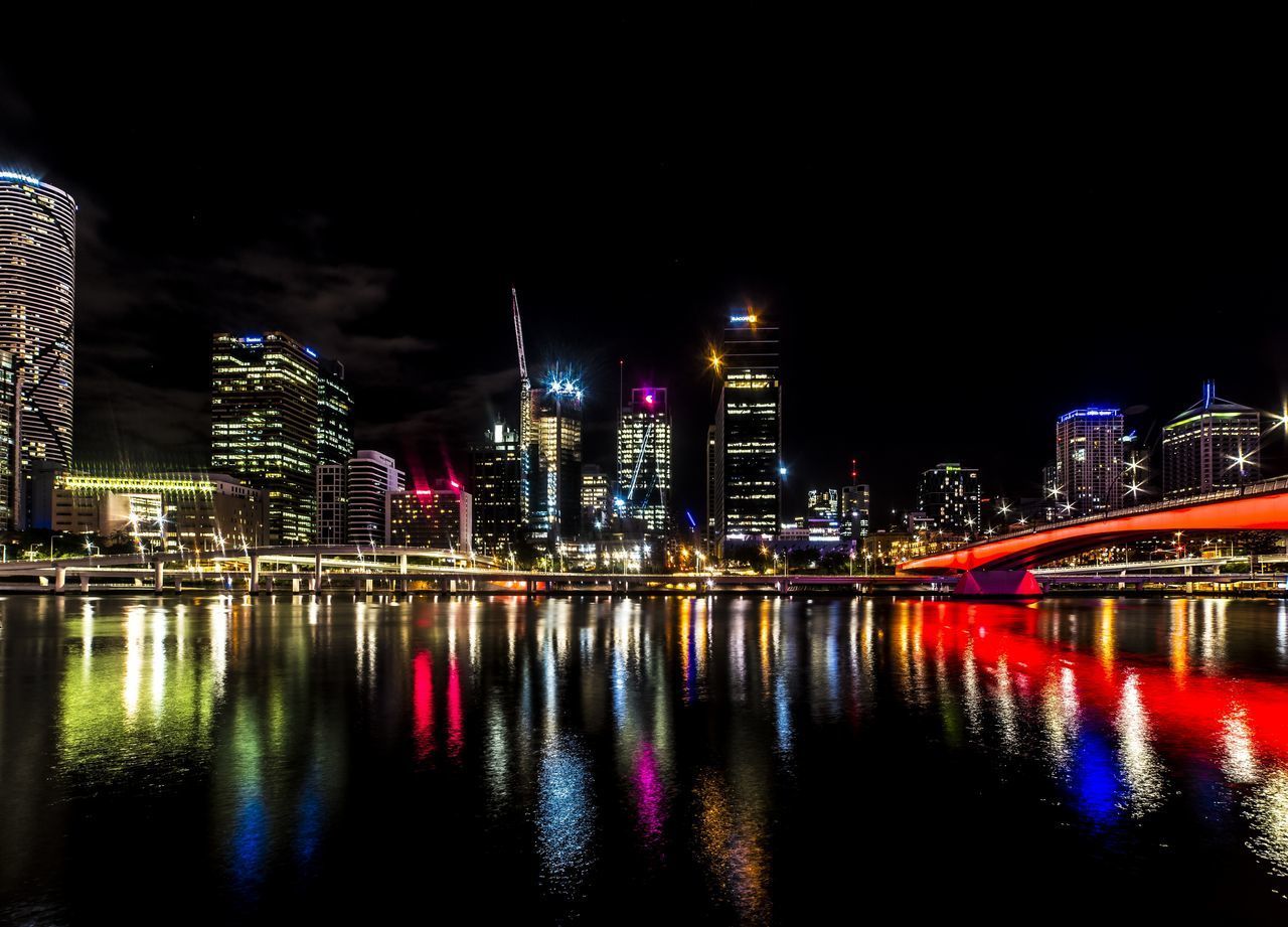 RIVER BY ILLUMINATED BUILDINGS AGAINST SKY AT NIGHT