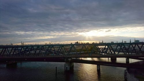 Bridge over river against cloudy sky