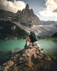 Man on rock by mountain against sky