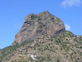 Low angle view of rocky mountain against clear blue sky