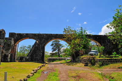 Arch bridge by road against blue sky