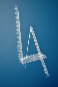 Low angle view of airplane flying against blue sky