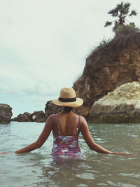 Rear view of shirtless man in sea against sky