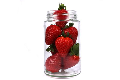 Close-up of strawberries in jar against white background