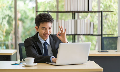 Young man using mobile phone while sitting on table