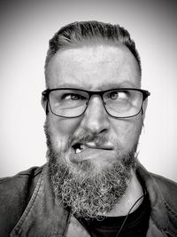 Close-up portrait of man wearing eyeglasses against gray background