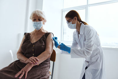 Doctor vaccinating senior patient at clinic