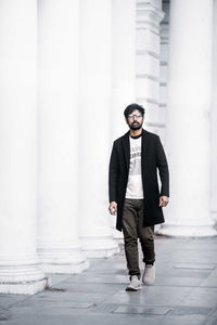 Full length portrait of young man standing against wall
