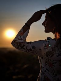 Side view of woman against sky during sunset