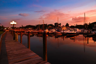 Boats moored at harbor during sunset