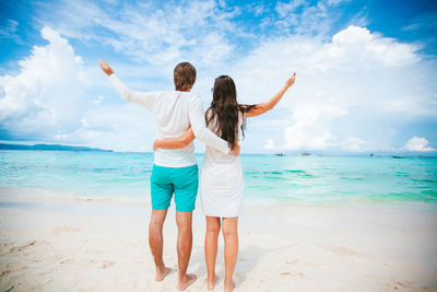 Rear view of friends standing on beach