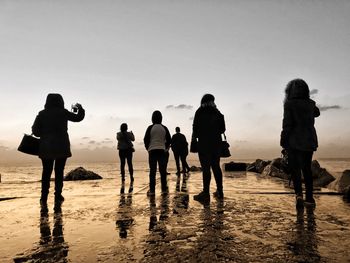 Rear view of silhouette people on pier against sky