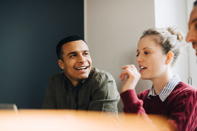 Low angle view of smiling businessman looking at businesswoman in creative office