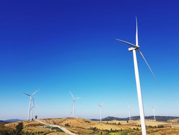 Wind turbines on land against clear blue sky