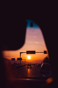 Cars on road against orange sky seen through car windshield