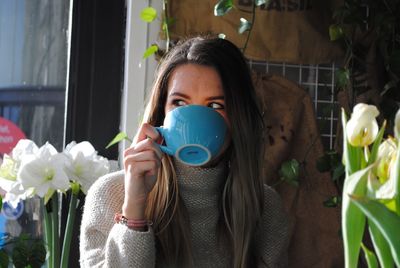 Girl drinking coffee in blue cup at home