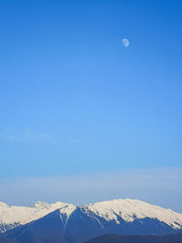 Scenic view of snowcapped mountains against blue sky