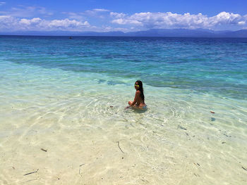 Side view of woman wearing bikini swimming in sea against sky