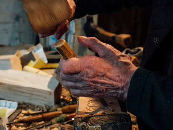 Midsection of man carving wood in workshop