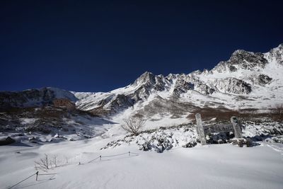 Scenic view of snow covered mountains against clear blue sky