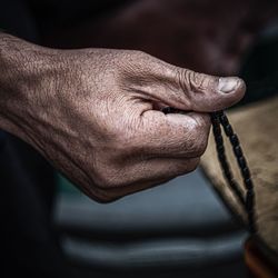 Midsection of man holding prayer beads