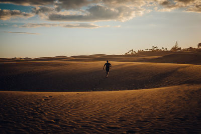 Full length rear view of man walking on desert