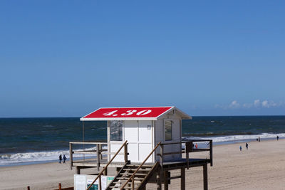 Lifeguard hut on beach against clear blue sky