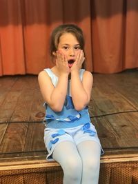 Portrait of shocked girl sitting on stage