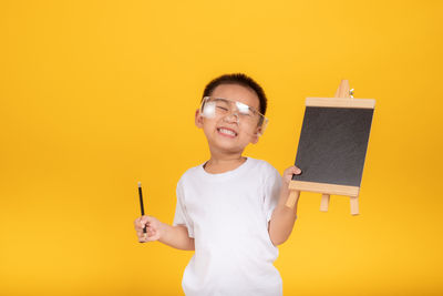 Portrait of smiling man standing against yellow background