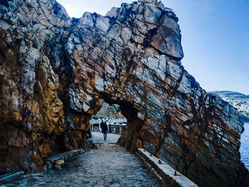 People walking on rocky mountain against sky