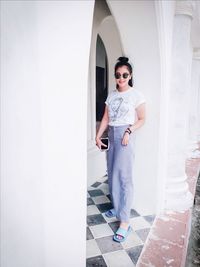 Portrait of young woman wearing sunglasses while standing at corridor