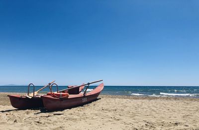Boat on beach against clear blue sky