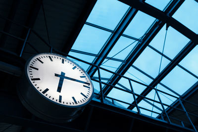 Public indoor clock and skyroof in train station at twilight, clock show time at rush hour