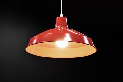 Close-up of illuminated pendant light over black background