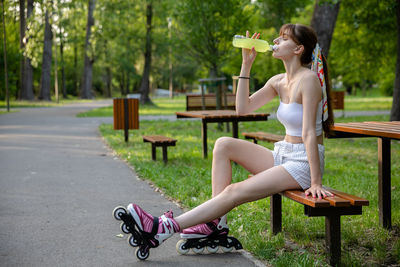 Full length of woman sitting on bench in park