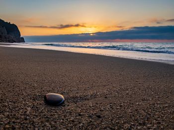 Surface level of beach against sky during sunset