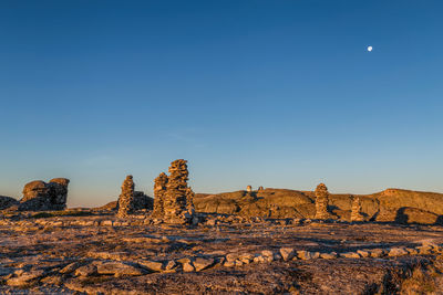 View of rock formations on landscape against blue sky